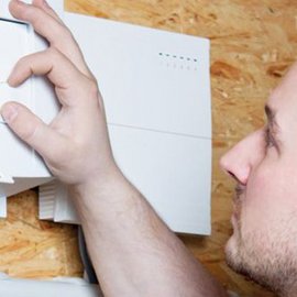 Der Handwerker überprüft sorgfältig die Installation eines weißen Geräts an einer Holzoberfläche.