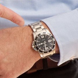 Die Hand eines Mannes mit einer stilvollen Uhr zeigt die Zeit an, während er in einem karierten Hemd gekleidet ist.